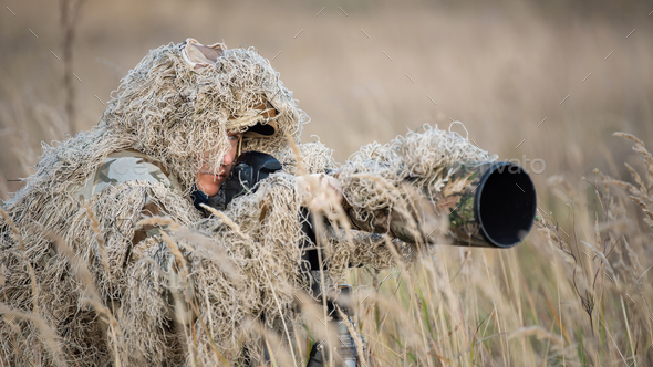 Wildlife photographer in the ghillie suit working - Stock Photo - Images